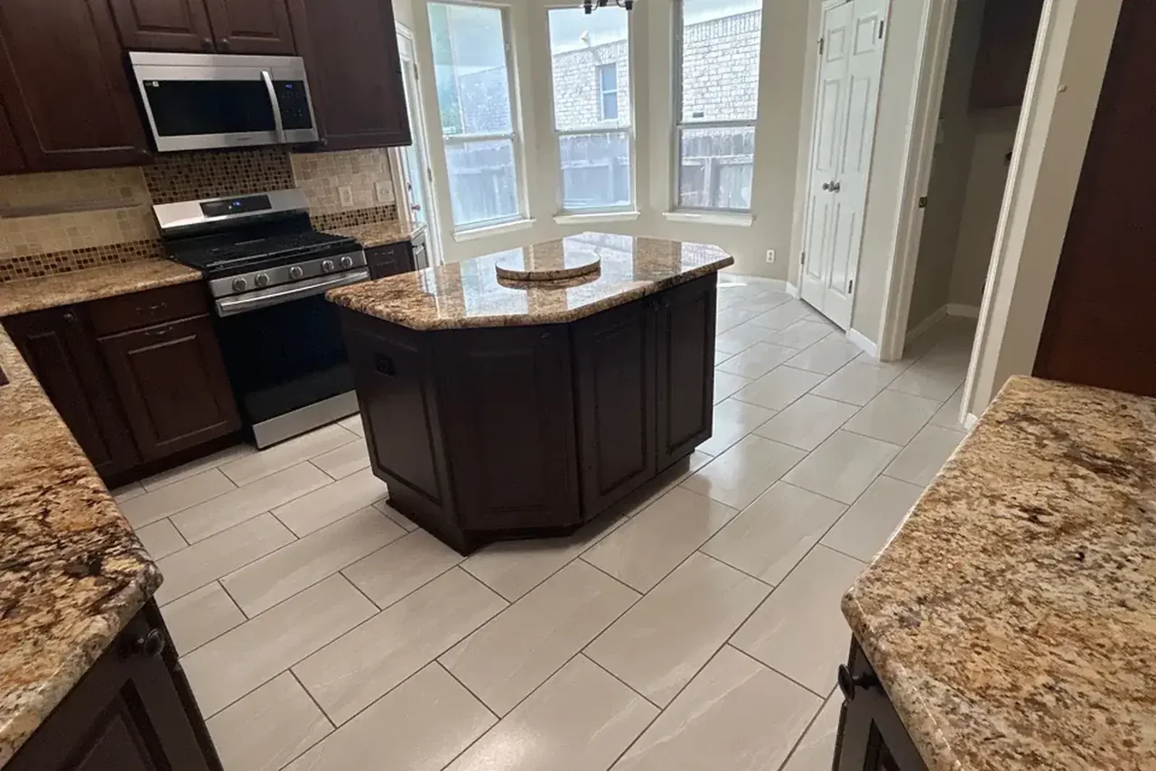 Completed Swept Up kitchen clean with dark cabinets, a granite island and light tile floors